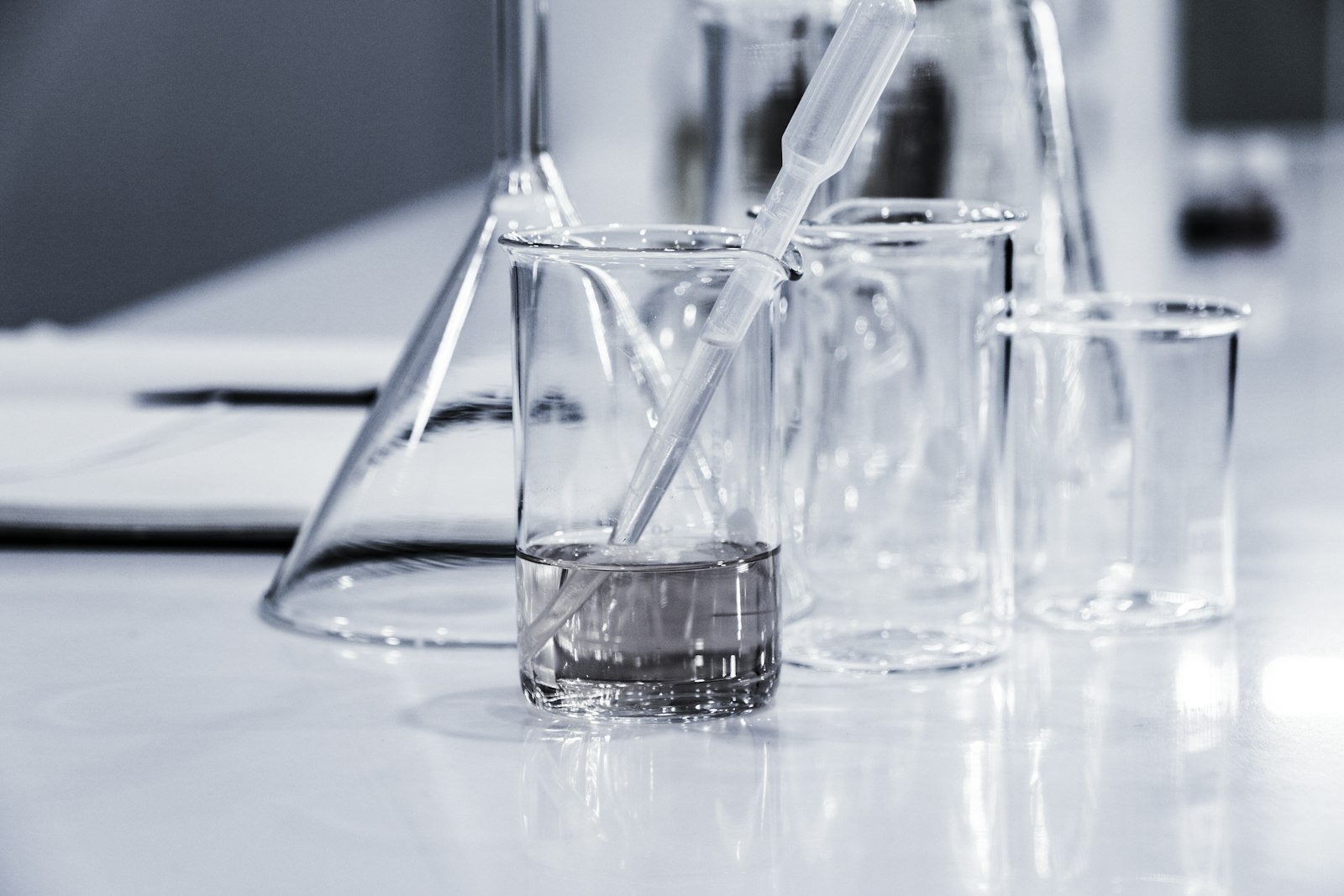 Laboratory glassware including beakers and a pipette on a clean surface.